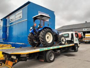 folami towing flatbed truck moving a tractor