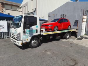 red vw being moved by a tow truck