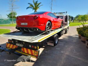red ferrari being moved by folami flatbed truck
